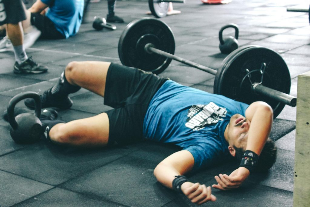Canva Man Lying on Rubber Mat Near Barbell Inside the Gym