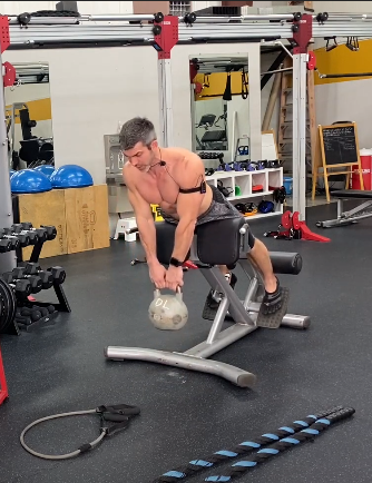weighted hyperextension in a machine with kettlebell
